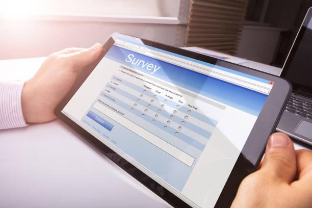 istock Person's Hand Holding Digital Tablet Showing Survey Form 915462714