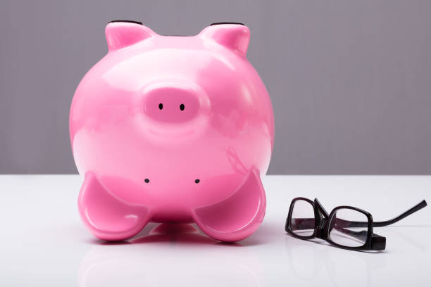 istock Upside Down Piggy Bank On Table With Eye Glasses 915462770