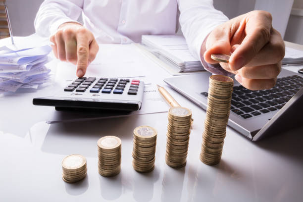 istock Business Person Counting Coins Using Calculator 915463064