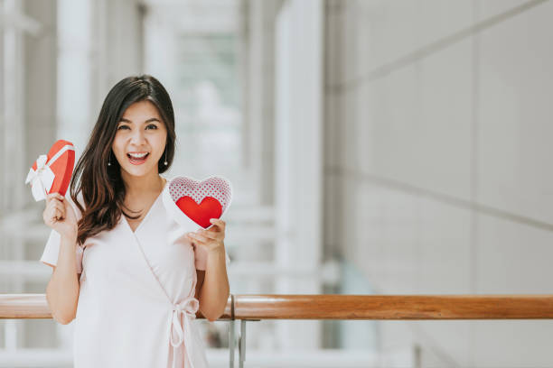 istock Asian woman holding gift box with red heart inside 915463238