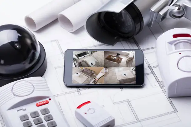 High Angle View Of Smart Home System On Mobilephone With Security Equipment And Blueprint