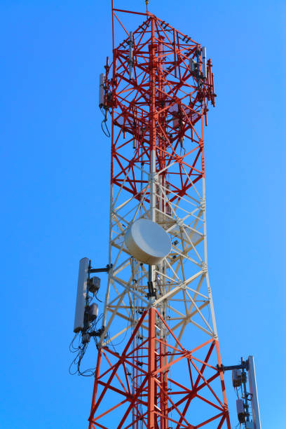 istock Mobile phone communication antenna tower with satellite dish on blue sky background 915483286