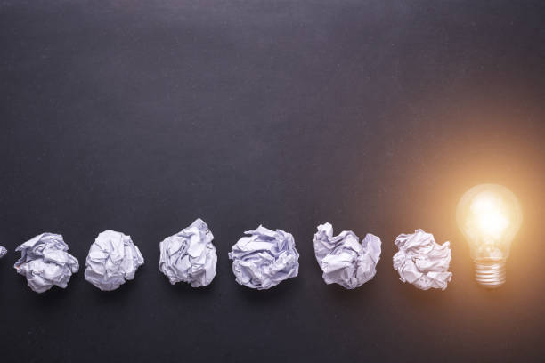 istock Top view crumpled paper and light bulbs on black stone board. Create idea concept 915486062
