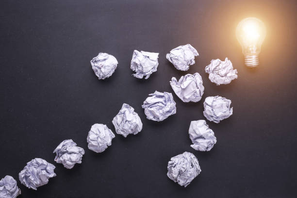 istock Top view crumpled paper and light bulbs on black stone board. Create idea concept 915486094