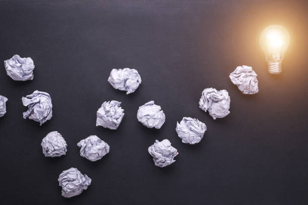 istock Top view crumpled paper and light bulbs on black stone board. Create idea concept 915486202