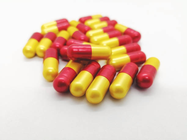 Medication and healthcare concept. Many red-yellow capsules of Amoxicillin500 mg. isolated on white background, used to treat many different types of infection caused by bacteria. Focus on foreground and copy space. concepto de medicamentos y atención médica. rojo-amarillo muchas cápsulas de amoxicillin500 mg. aislados en fondo blanco, que se usa para tratar a muchos tipos diferentes de infecciones causadas por bacterias. se centran en primer plano y copia espacio.