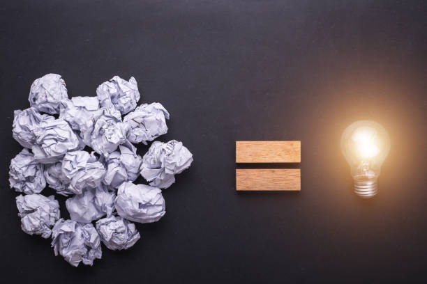 istock Top view crumpled paper and light bulbs on black stone board. Create idea concept 915487286