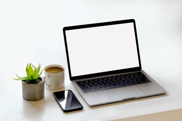 Mockup laptop, smartphone and coffee mug on white desk.
