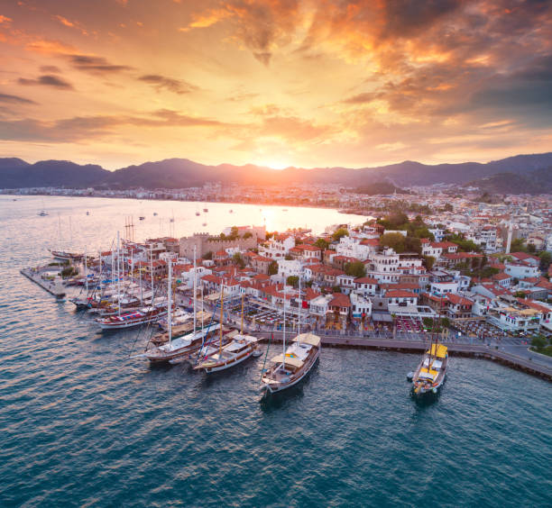 aerial view of boats and yachts and beautiful architecture at sunset in marmaris, turkey. landscape with boats in marina bay, sea, city, mountains, colorful sky. top view from drone of harbor. travel - marina nautical vessel sailboat harbor imagens e fotografias de stock