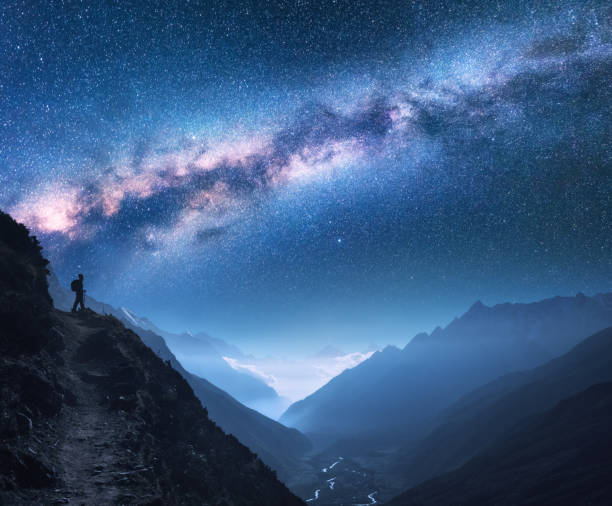 space with milky way, girl and mountains. silhouette of standing woman on the mountain peak, mountains and starry sky at night in nepal. sky with stars. trekking. night landscape with bright milky way - mountain himalayas aerial view landscape imagens e fotografias de stock