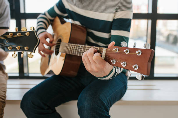 istock Learning to play the guitar. Extra-curricular lessons for adults. Music education. Masterclass playing the guitar 915541564