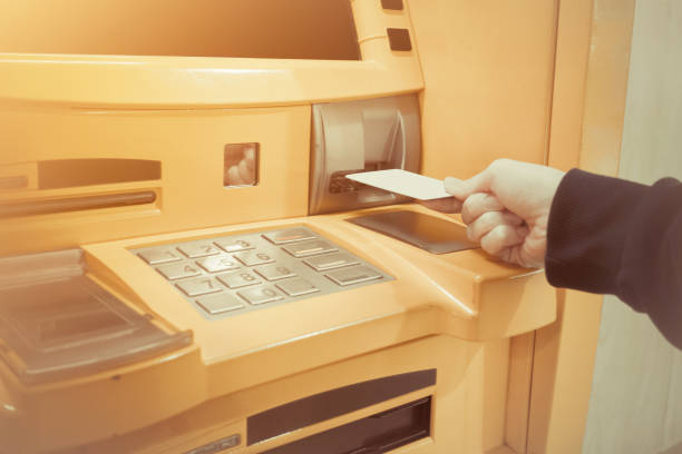 istock Close-up of woman's hand inserting debit card into an ATM machine 915547316