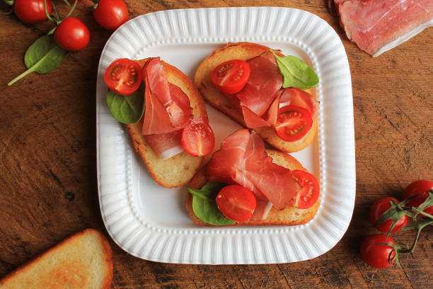 bruschetta with prosciutto ham, cherry tomatoes and green spinach . top view - bruschetta cutting board italy olive oil imagens e fotografias de stock