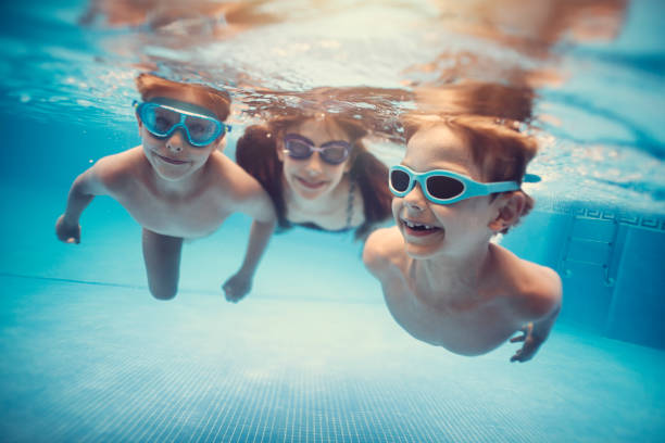 istock Happy kids swimming underwater in pool 915553350