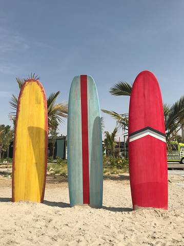 Three colorful surfboards stand on the beach.