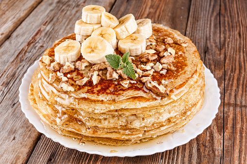 A pile of pancakes with honey ,  banana and nuts. Healthy breakfast. Shrovetide. Russian pancakes.