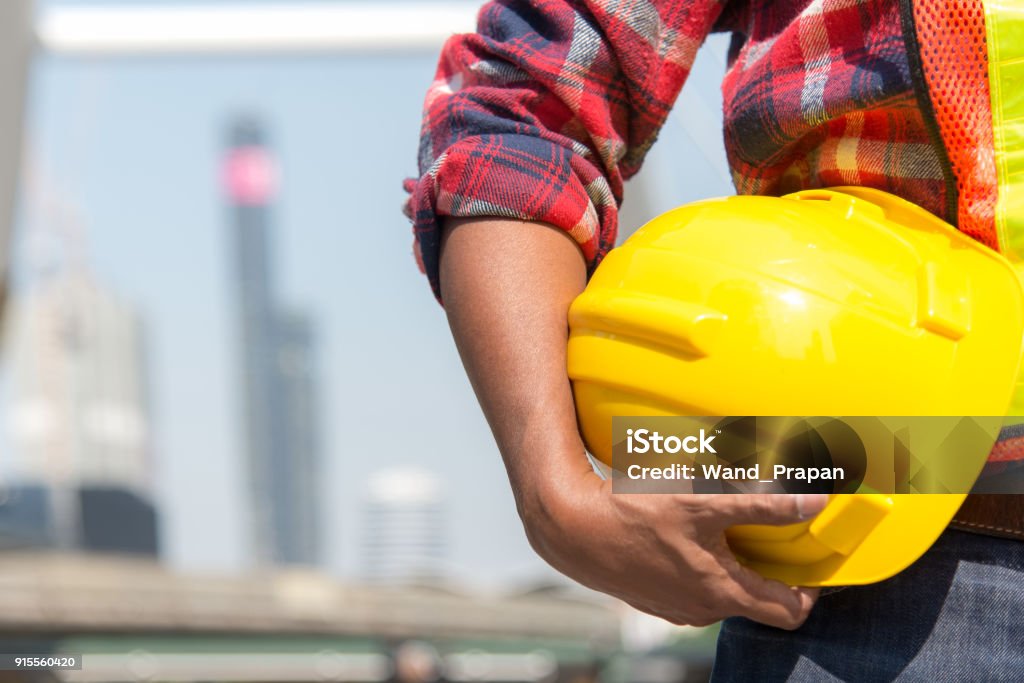 Trabajador de arquitecto con casco amarillo una para el control de seguridad de los trabajadores en el sitio de la ciudad. - Foto de stock de Casco Duro libre de derechos