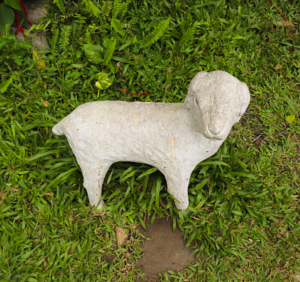 A white concrete dog statue in Danang cathedral in Vietnam, that is located in cathedral garden.