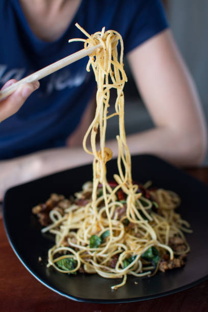 istock woman eating stir-fried spaghetti with Sai Aua (Notrhern Thai Spicy Sausage) 915568086
