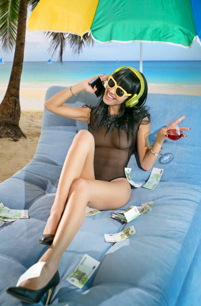 mujer con auriculares en la playa - currency women luxury wealth fotografías e imágenes de stock