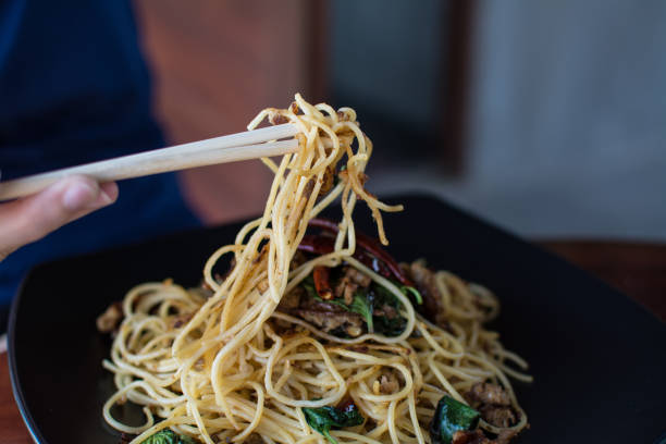 istock woman eating stir-fried spaghetti with Sai Aua (Notrhern Thai Spicy Sausage) 915570596