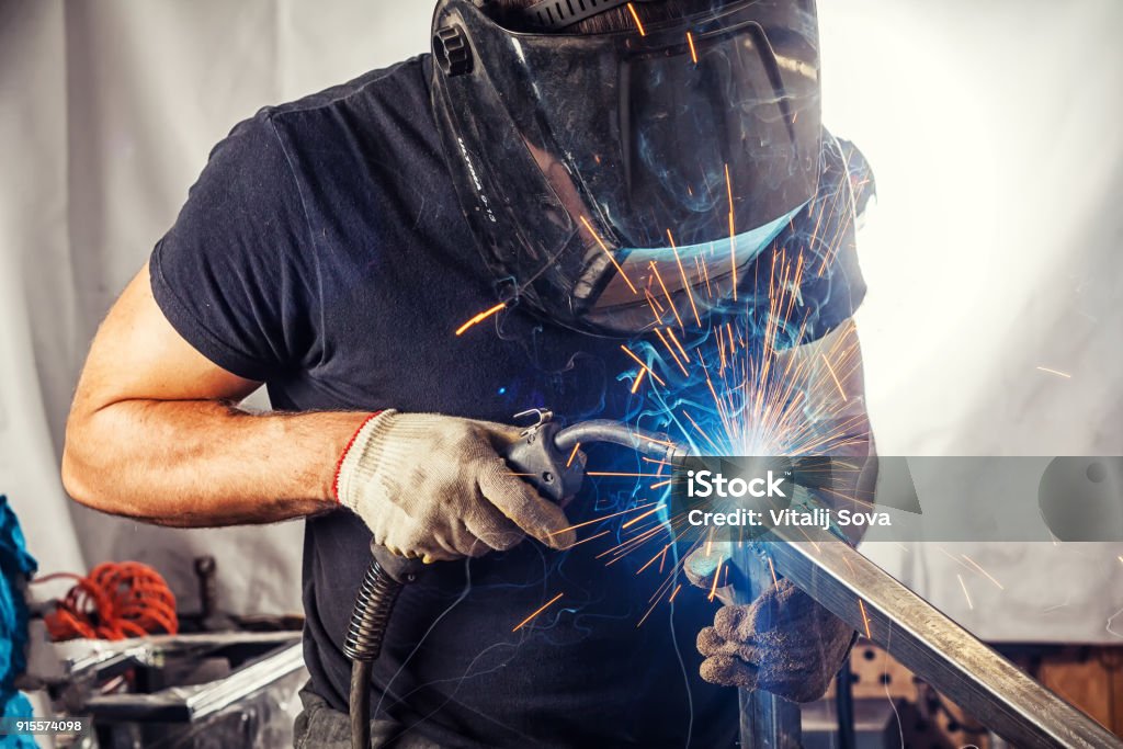 hombre soldar un metal con una máquina de soldar - Foto de stock de Soldador libre de derechos