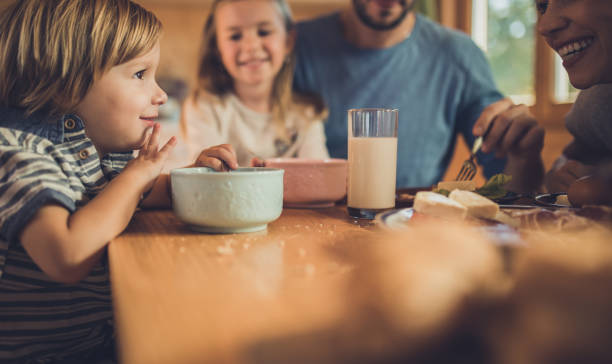 Small boy having breakfast with his family in dining room.