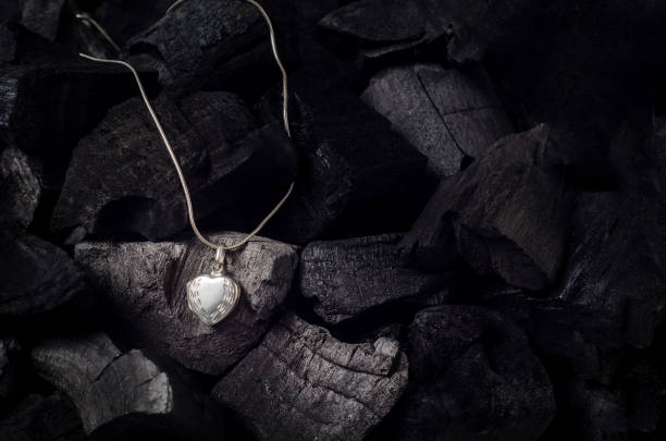 istock Silver heart  shape locket with necklace on black charcoal texture background 915593906