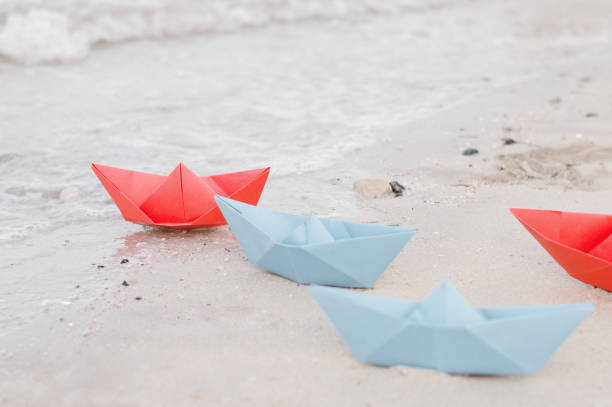 istock Paper ships of blue and red color on sandy beach 915601968
