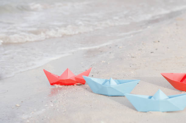 istock Red and blue paper ships on the beach 915604188