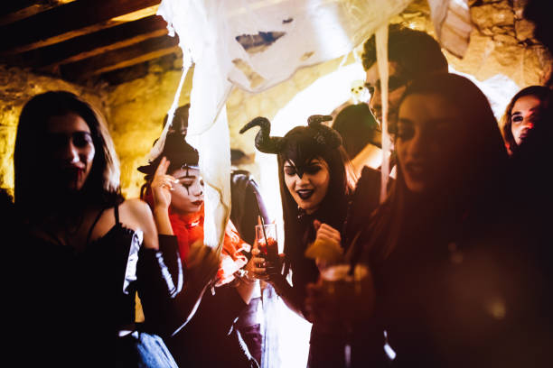 jeunes amis dans des costumes d’halloween danser et boire à parti - witches & vampires photos photos et images de collection