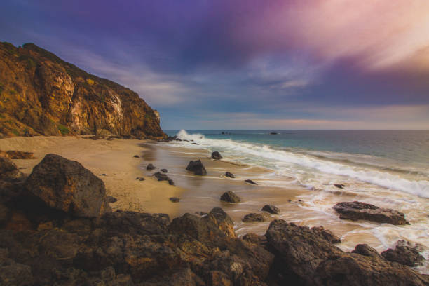 Secluded Pirate's Cove Beach at sunset with a colorful sky and ocean water flowing around rock formations, Point Dume, Malibu, California