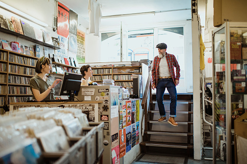 Senior man walking into a record store and greeting the staff.