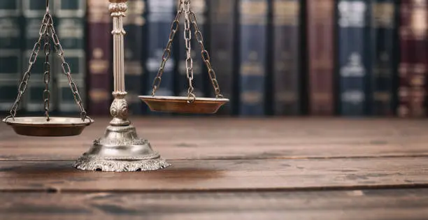 Photo of Scales of Justice and Law books on a  wooden background.