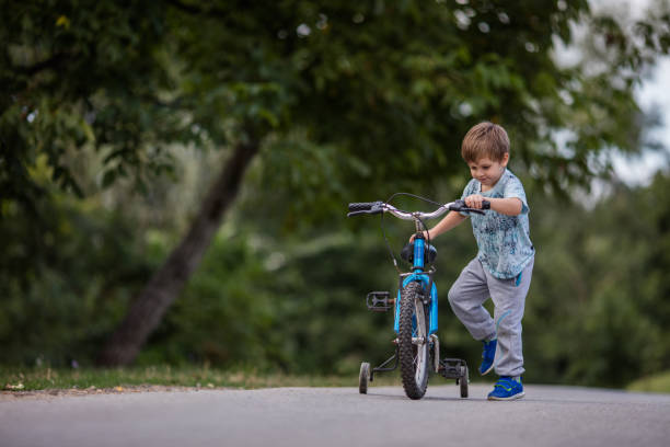 istock Little boy getting on his bicycle in the park. 915628964
