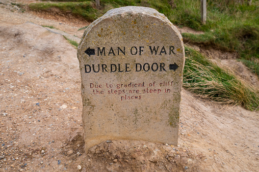 A marker on the South West Coast Path showing directions to Durdle Door and Man of War in Dorset, UK.