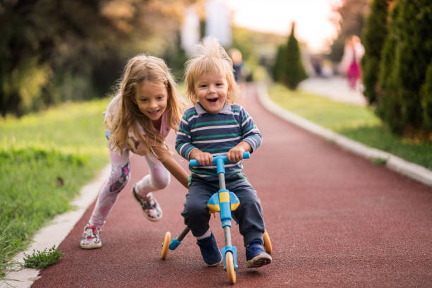 istock Happy boy having fun on tricycle while his sister is pushing him. 915629988