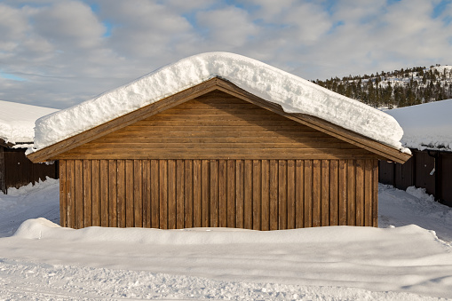 Snow on a garage roof in Brokke, Setesdal in Norway. Winter. Brown garage wall.