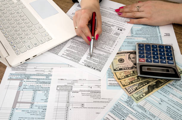 istock tax form 1040, laptop, hands, money 915633362