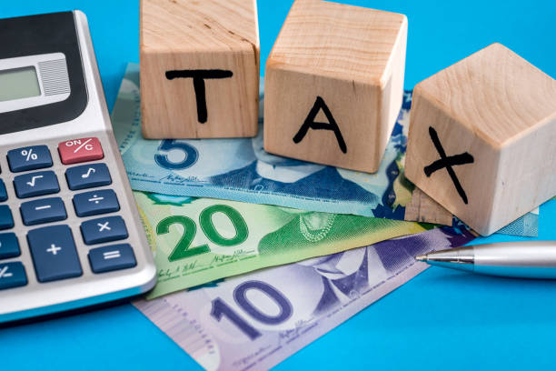 Wooden cubes with letters that spell tax lying down on cash