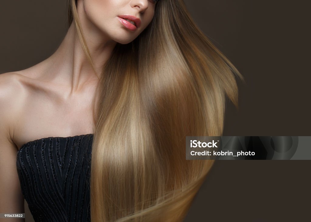 Beautiful blond girl with a perfectly smooth hair, classic make-up. Beauty face Beautiful blond girl with a perfectly smooth hair, classic make-up. Beauty face. Picture taken in the studio. Hair Stock Photo