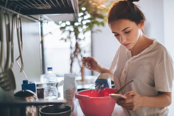 Young woman in the kitchen, reading recipe from the internet