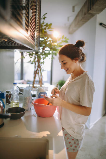 istock Young woman in the kitchen, reading recipe from the internet 915637902