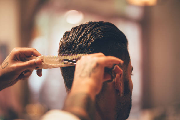 primo piano delle mani dell'hairstylist che tagliano la ciocca dei capelli dell'uomo - men hairdresser human hair hairstyle foto e immagini stock