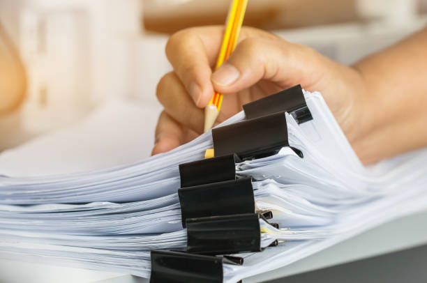 istock Businessman hands searching and checking write unfinished documents stacks of paper files on office desk for report papers with pencil, piles of sheet achieves clips, Document is written, drawn,presented. 915645320