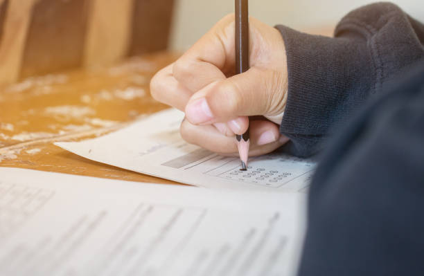 istock Students concentration holding pencils in hand doing multiple-choice quizzes testing exams answer sheets exercises in school, 915645386