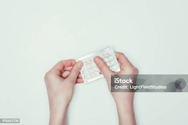 Cropped Shot Of Woman Holding Contraceptive Pills In Hands Isolated On Grey Stock Photo - Download Image Now