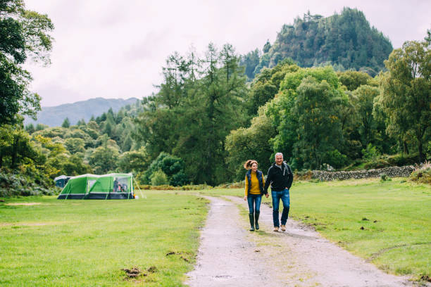 Senior Couple Hiking Together Senior couple are enjoying a scenic walk through the woodlands at the Lake District. keswick photos stock pictures, royalty-free photos & images