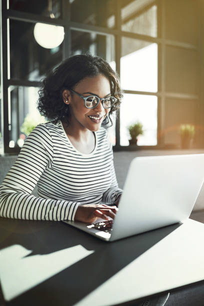 istock Smiling young African woman sitting at a table working online 915653366