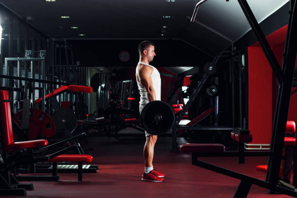 istock Young man exercising with barbell weight in the gym. 915655502
